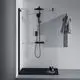 Duschsystem von Ideal Standard mit schwarzem Duschkopf, Handbrause an einer Glaswand und Handtuchhalter. Auf der Duschwanne stehen Pflegeprodukte in einer Schale.